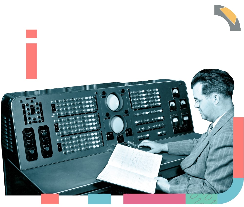 A vintage image of a man in front of a large computer reading a book